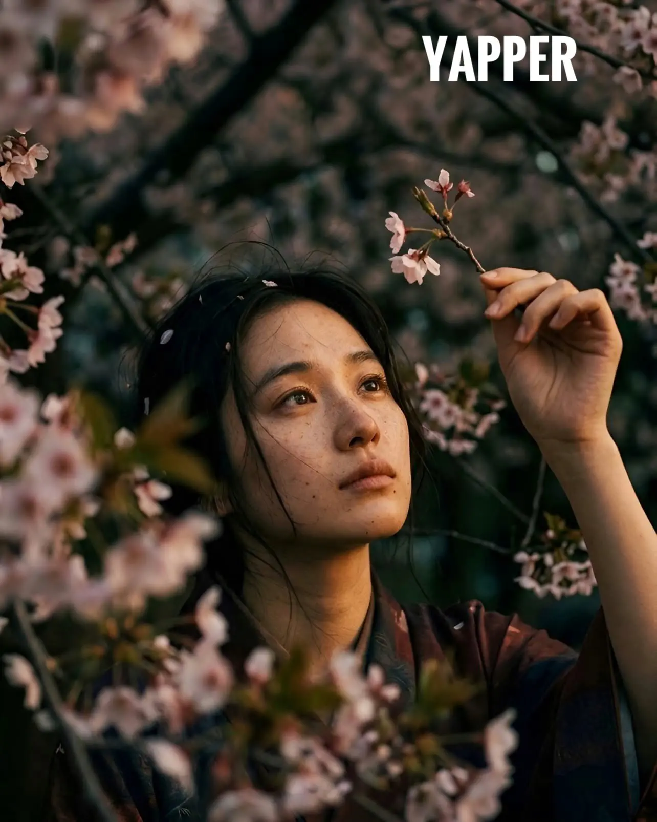 trend prompt: young Japanese woman wearing a vintage kimono in muted tones sitting beneath dense cherry blossom branches, gently holding a small cherry blossom twig and looking up at it with a quiet, melancholic