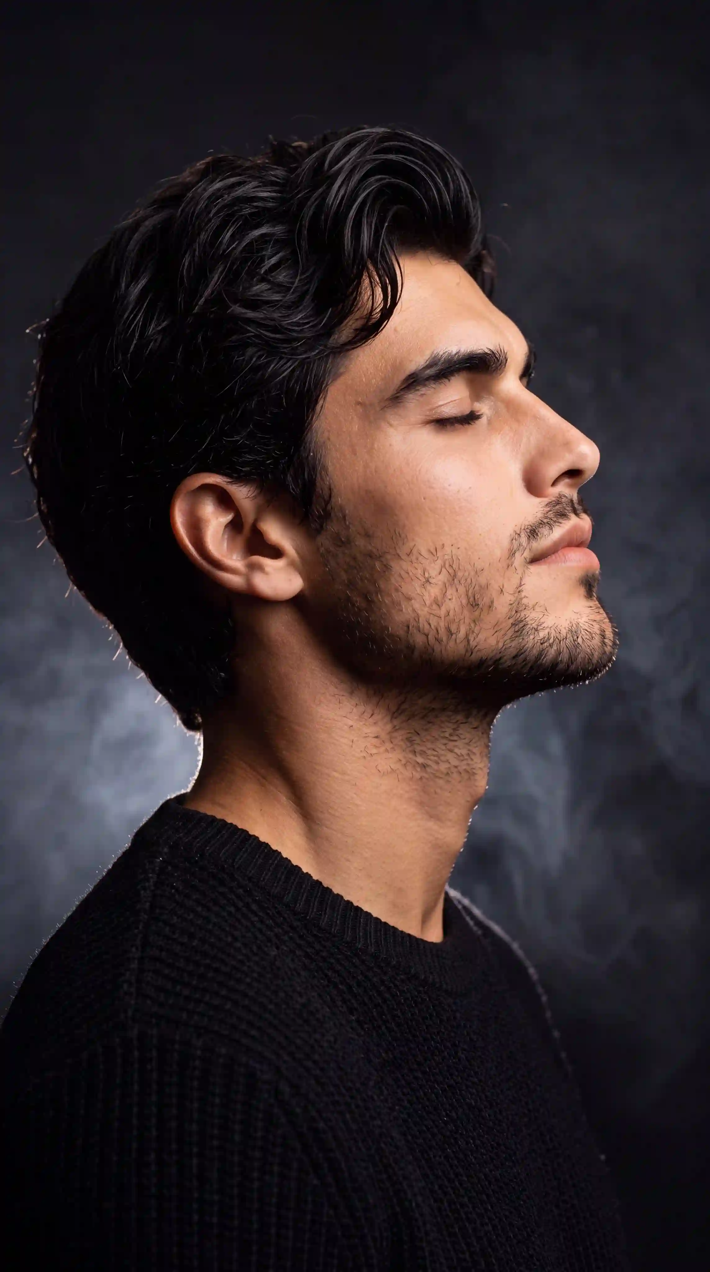 trend prompt: Use my uploaded image as the exact facial reference. Preserve my identity with maximum accuracy, including my face shape, hairstyle, beard, eyebrows, skin tone, eye proportions, nose, lips, jawline, ears, and every unique facial feature. Do not alter my age, expression, or recognizable appearance. Create an ultra-realistic, cinematic side-profile portrait with my head gently tilted upward, eyes peacefully closed, conveying calmness, confidence, and deep introspection. Dress me in a premium black textured knit sweater with a clean, minimal aesthetic. Place me against a deep matte-black studio background filled with soft drifting smoke and subtle atmospheric haze. Use dramatic low-key lighting with a gentle rim light outlining my hair, beard, and jawline, while a soft key light elegantly illuminates my face, creating rich contrast and depth. Keep the composition minimal and luxurious, emphasizing negative space. Capture ultra-sharp skin texture, realistic beard details, natural hair strands, and flawless facial proportions. Professional editorial photography, 85mm lens, f/1.8, shallow depth of field, HDR, ultra-photorealistic, premium color grading, soft cinematic shadows, IMAX-quality, 8K resolution, masterpiece, award-winning portrait, no text, no watermark, no artifacts, no facial distortion, no extra limbs, no blur.